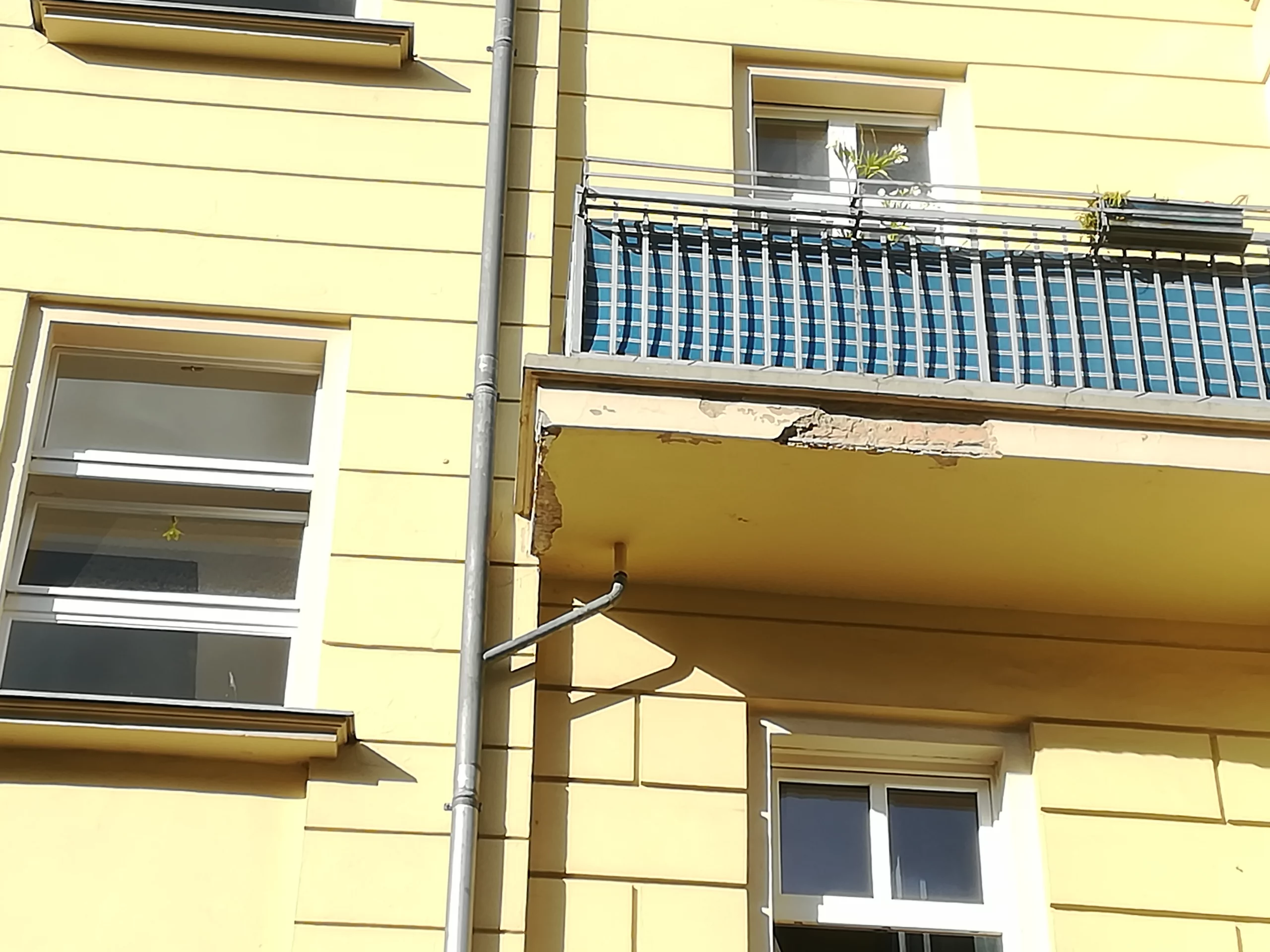 Losen Putz an einer beschädigten Balkonplatte zur Erstsicherung der Fassade entfernen.
